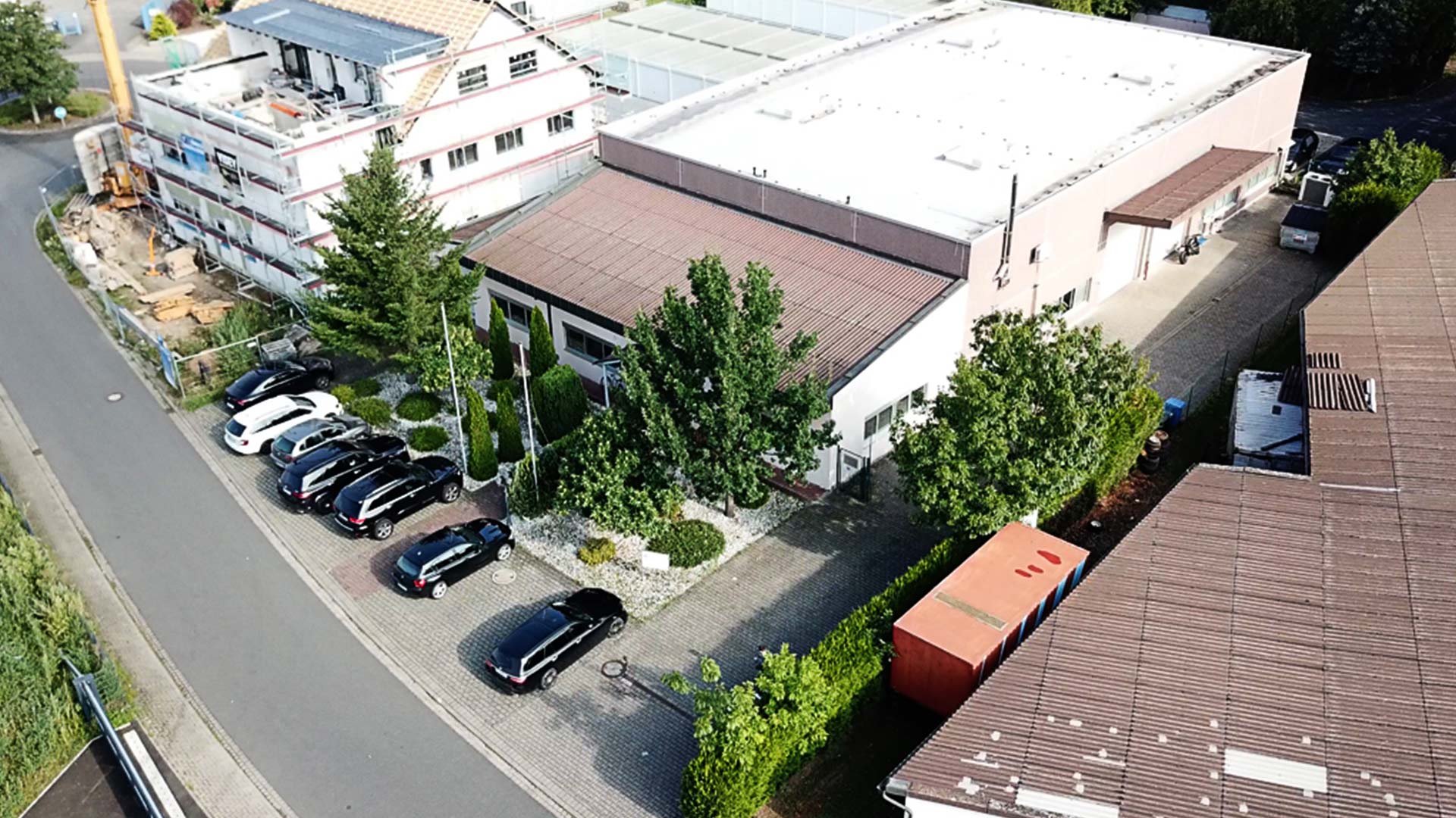 Luftaufnahme des TRISON-Bürogebäudes in Kleinostheim bei Frankfurt, Deutschland, umgeben von Bäumen und Parkplatz.