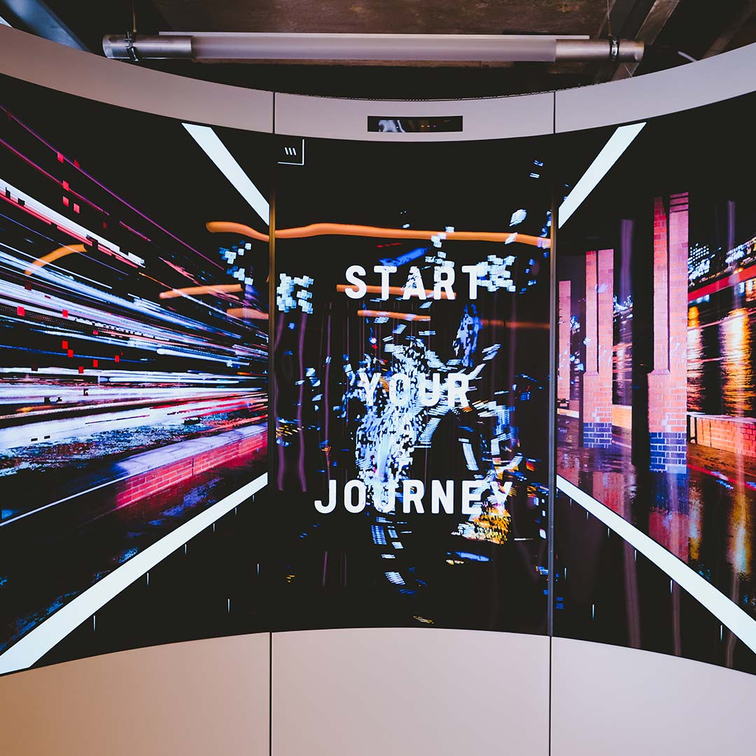 Curved LED display showing Start Your Journey content inside the adidas London flagship store