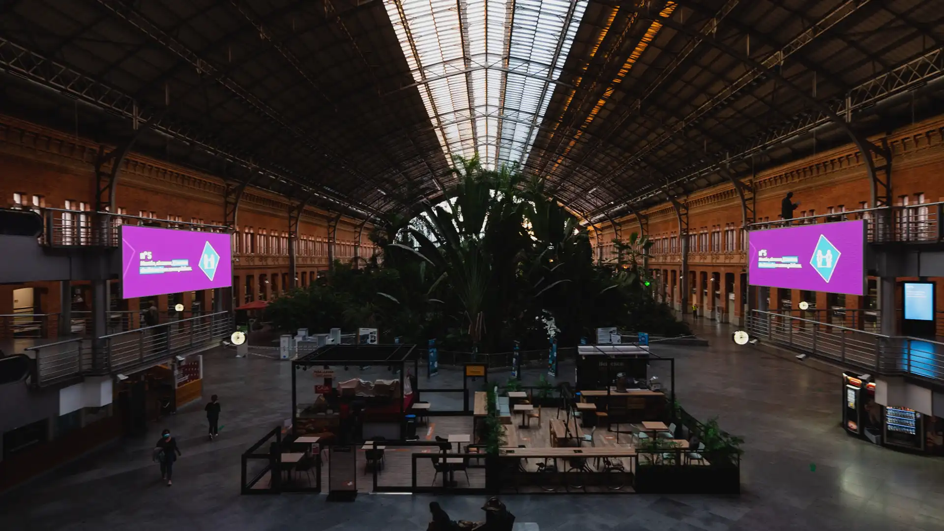 Großaufnahme der belebten Halle von Atocha mit Reisenden, die die LED-Bildschirme betrachten.