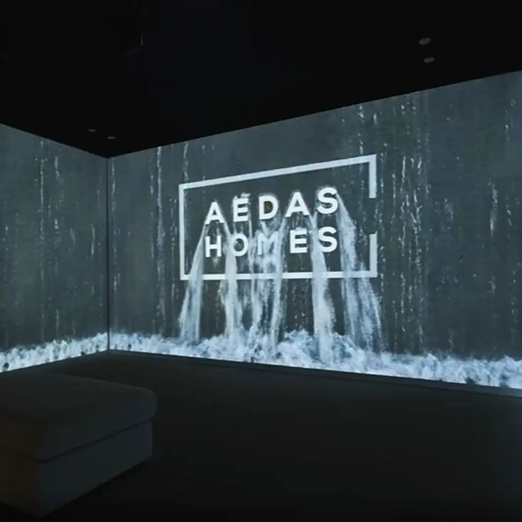 Zona de proyección sensorial con visuales dinámicos que refuerzan la identidad de marca de AEDAS HOMES.