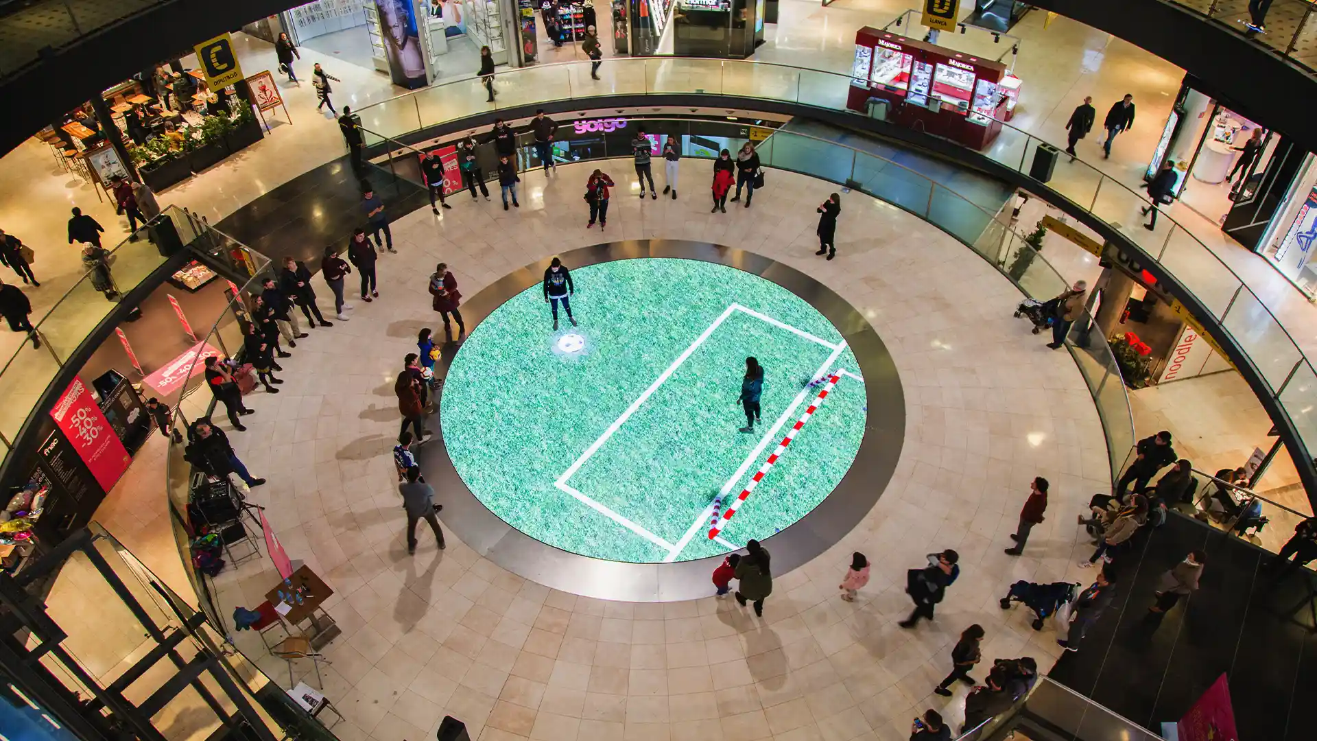 Installation LED dans un centre commercial à Arenas Barcelona avec sol interactif et visiteurs interagissant avec des contenus digitaux.