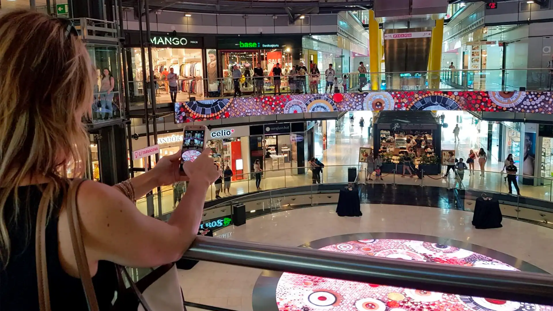 nstallation LED dans un centre commercial à Arenas Barcelona avec contenus digitaux sur grands écrans et visiteur capturant l’expérience.