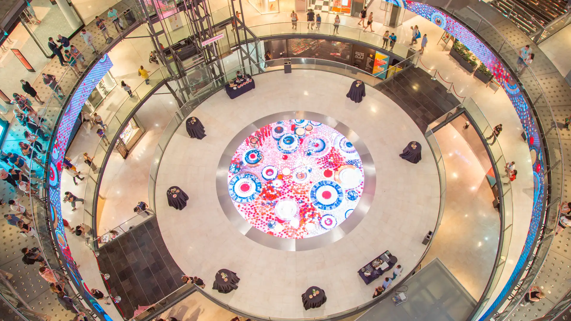 Installation LED dans un centre commercial à Arenas Barcelona avec un affichage circulaire interactif au sol et des visiteurs autour de l'espace.