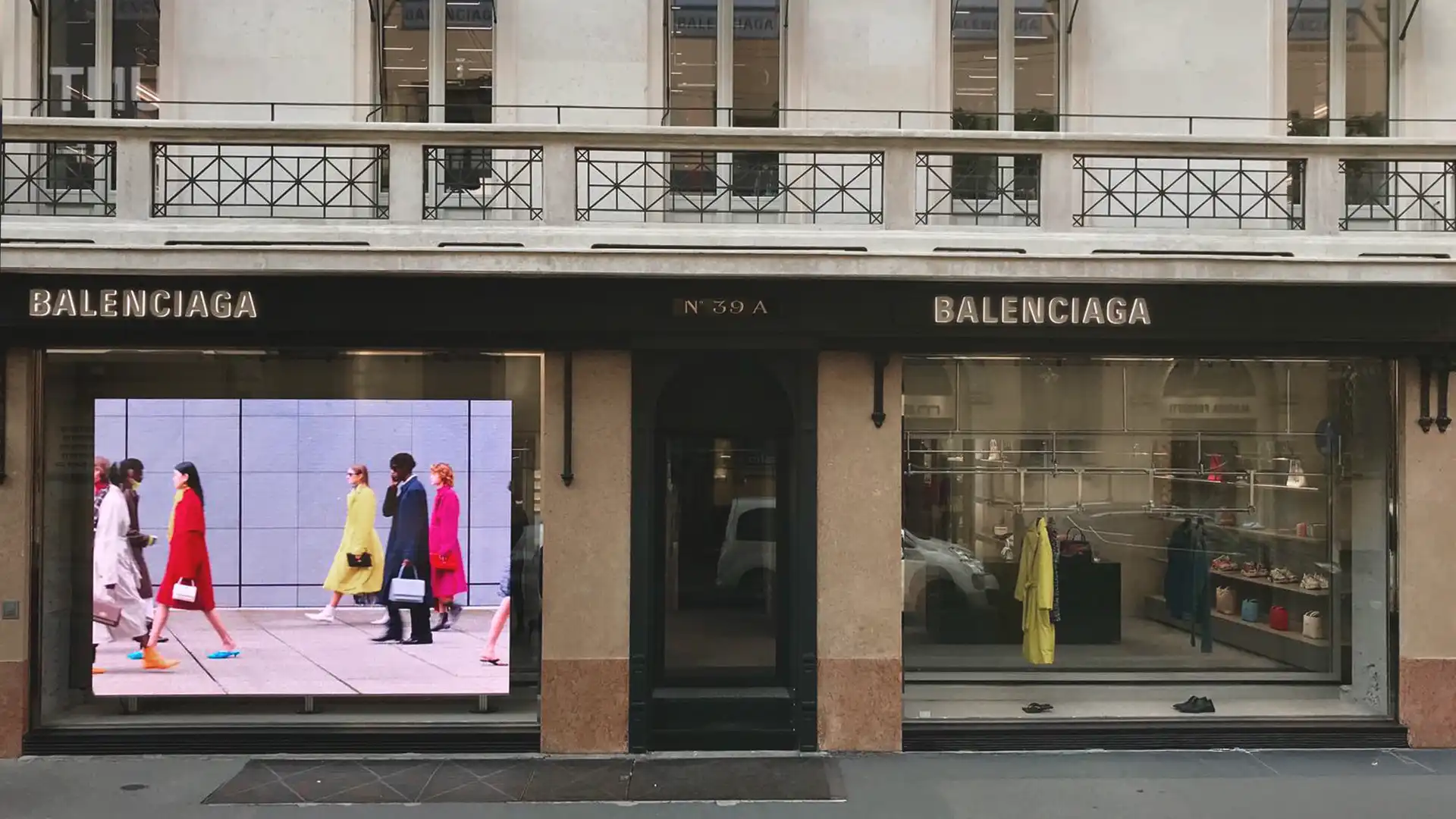 Vista exterior de la tienda insignia de Balenciaga en Milán, con una pantalla LED de gran formato integrada en la fachada minimalista.