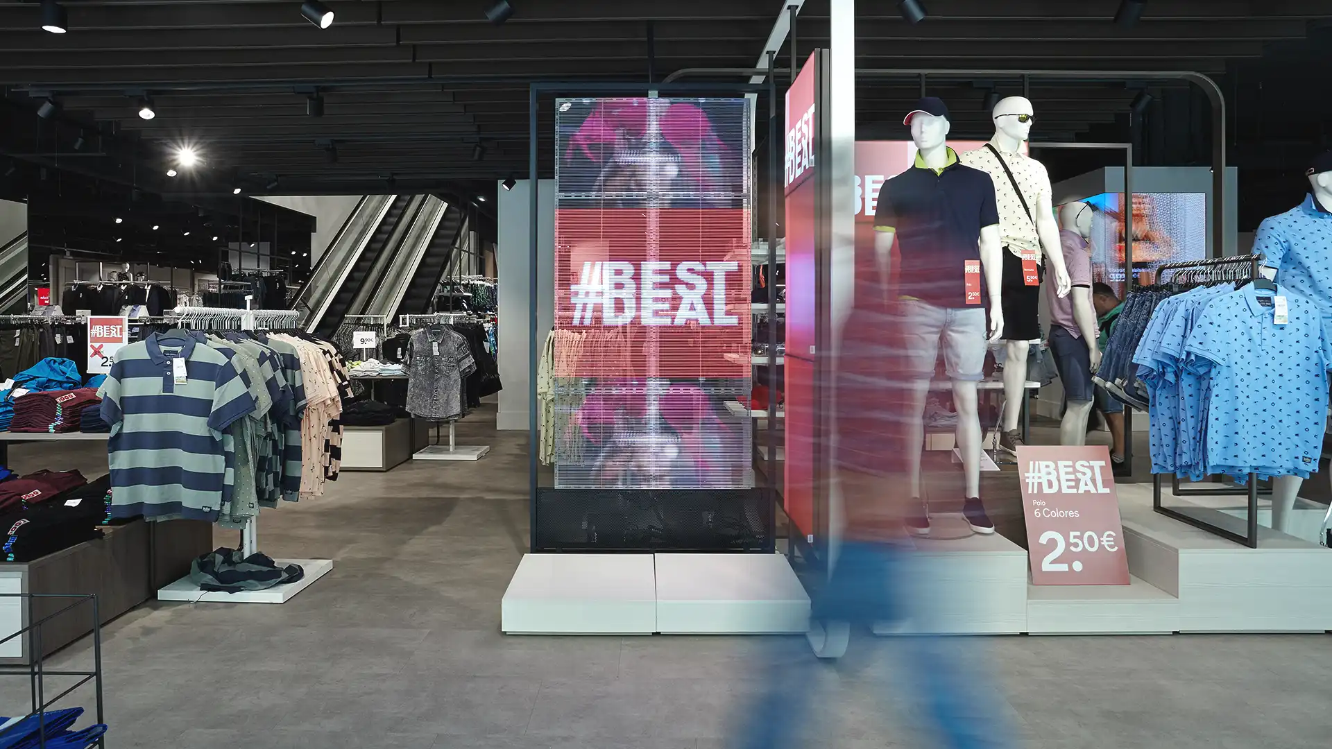 Intérieur d'un magasin C&A avec des écrans numériques synchronisés assurant une communication visuelle unifiée.