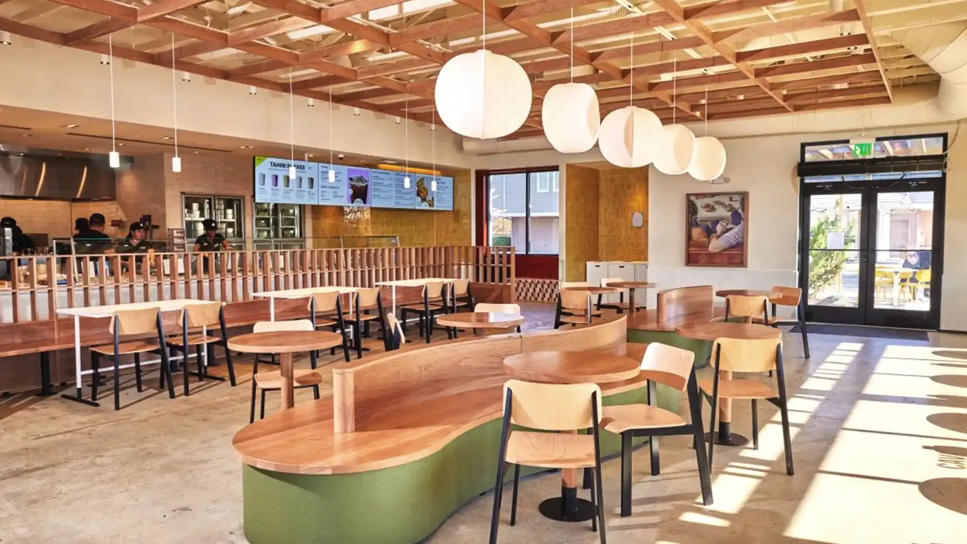 Interior view of a CAVA restaurant with synchronized digital menus and brand visuals integrated by TRISON North America.