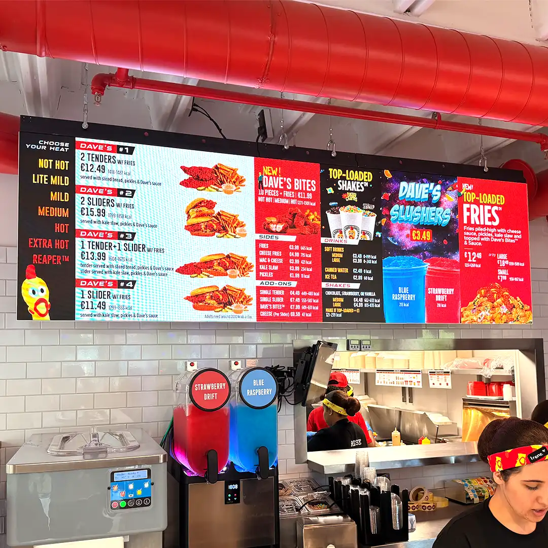 Digital menu board displaying heat levels, combo meals, and seasonal pricing at a Dave's Hot Chicken UK location