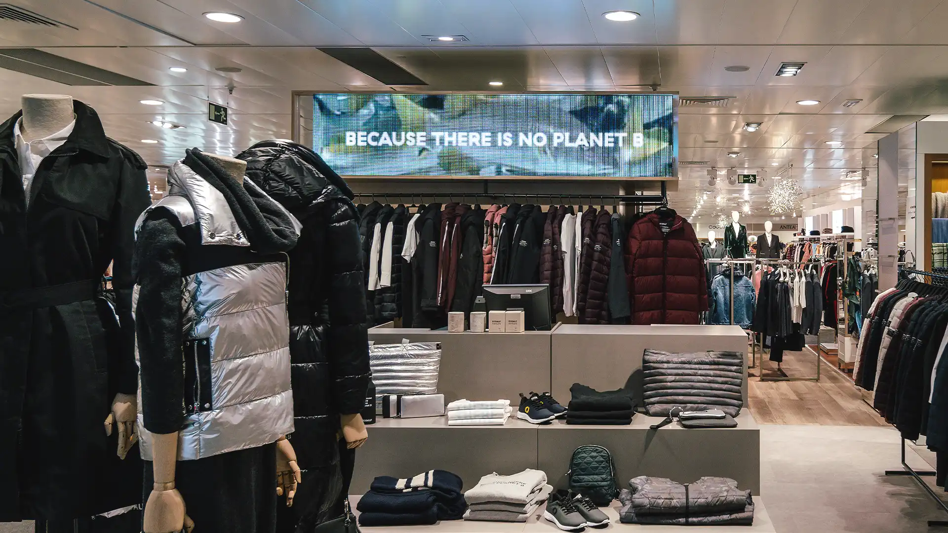 Totem LED intégré de manière transparente dans le design du magasin Ecoalf, indiquant le contenu de la production durable.