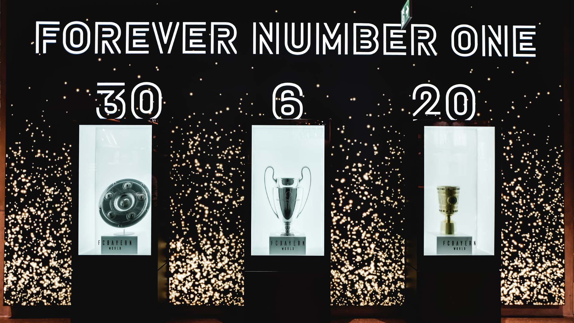 Three LED display towers presenting FC Bayern München trophies under Forever Number One signage at FCBayern World Munich