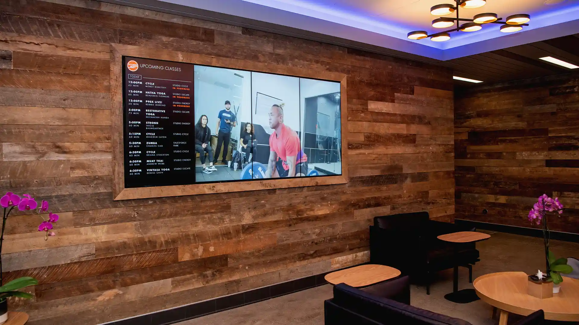 Fitnessraum SF mit digitalen Bildschirmen, die Informationen über die Kurse anzeigen.