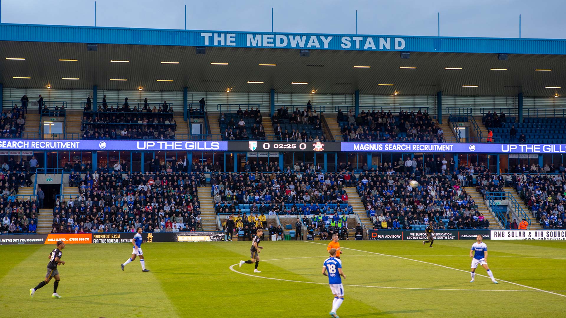 Aficionados del Gillingham FC celebrando en el Priestfield Stadium con las pantallas LED visibles en el Medway Stand