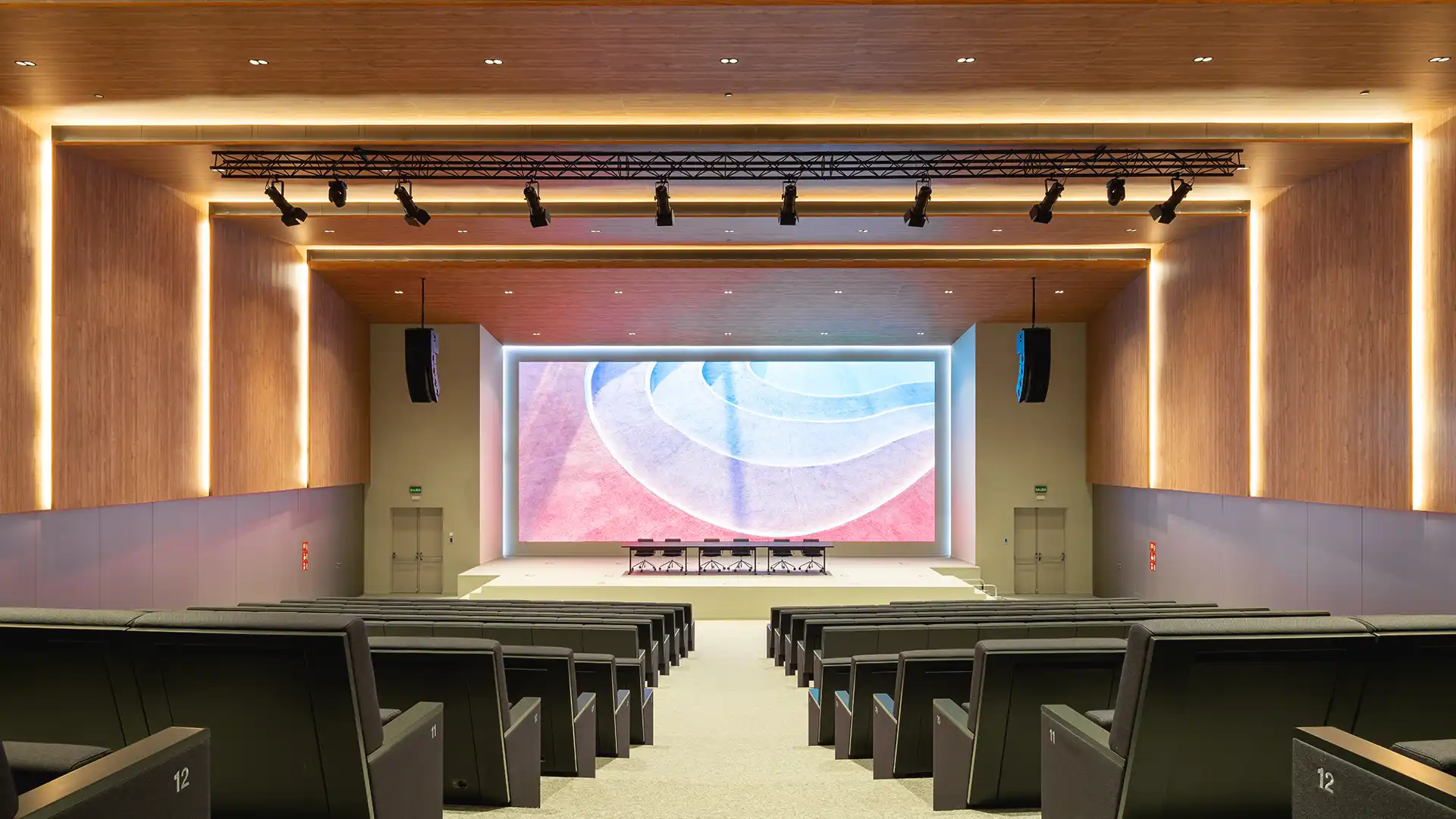 Vista panoramica dell'auditorium aziendale rinnovato di CORTIZO con schermo LED integrato e un moderno design dell'illuminazione.