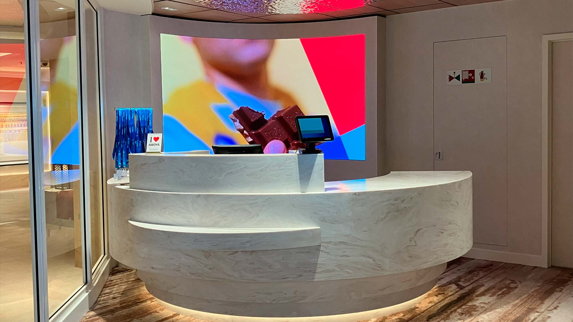 Curved LED wall and reception desk integrated by TRISON Germany in Heinemann retail area on a cruise ship