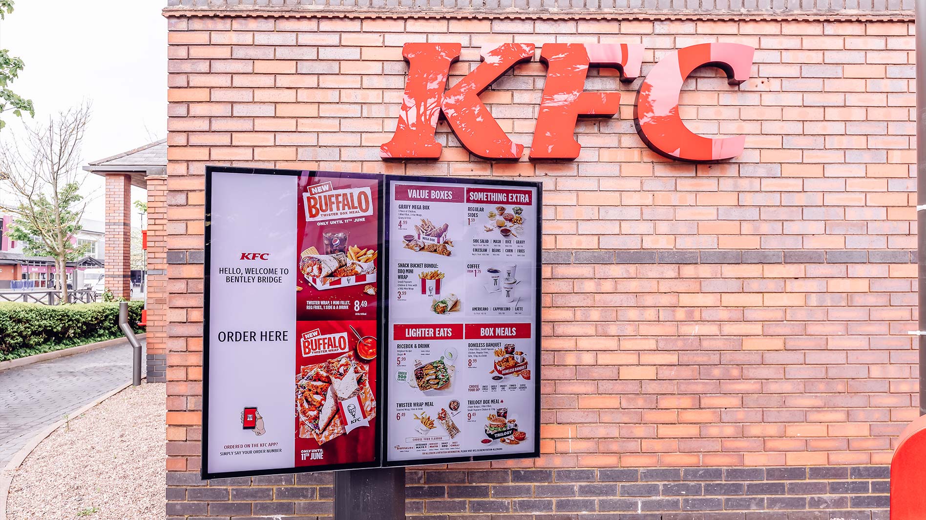 Dual outdoor digital menu boards at a KFC Drive Thru in the UK displaying current menu and pricing