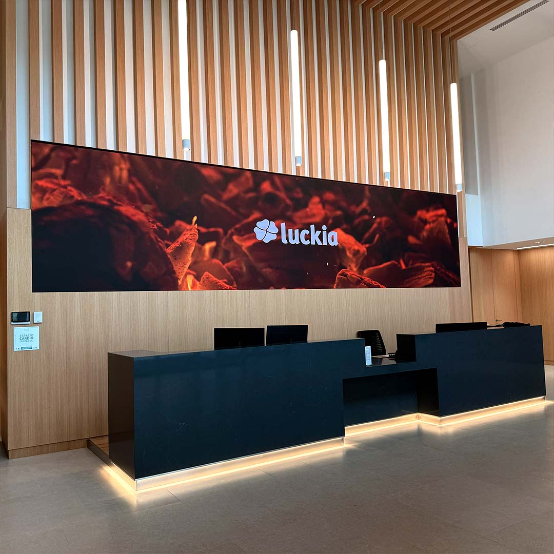 Panoramaansicht des Empfangsbereichs der Luckia-Zentrale mit vollständiger LED-Displaywand und Gebäudezugang, A Coruña