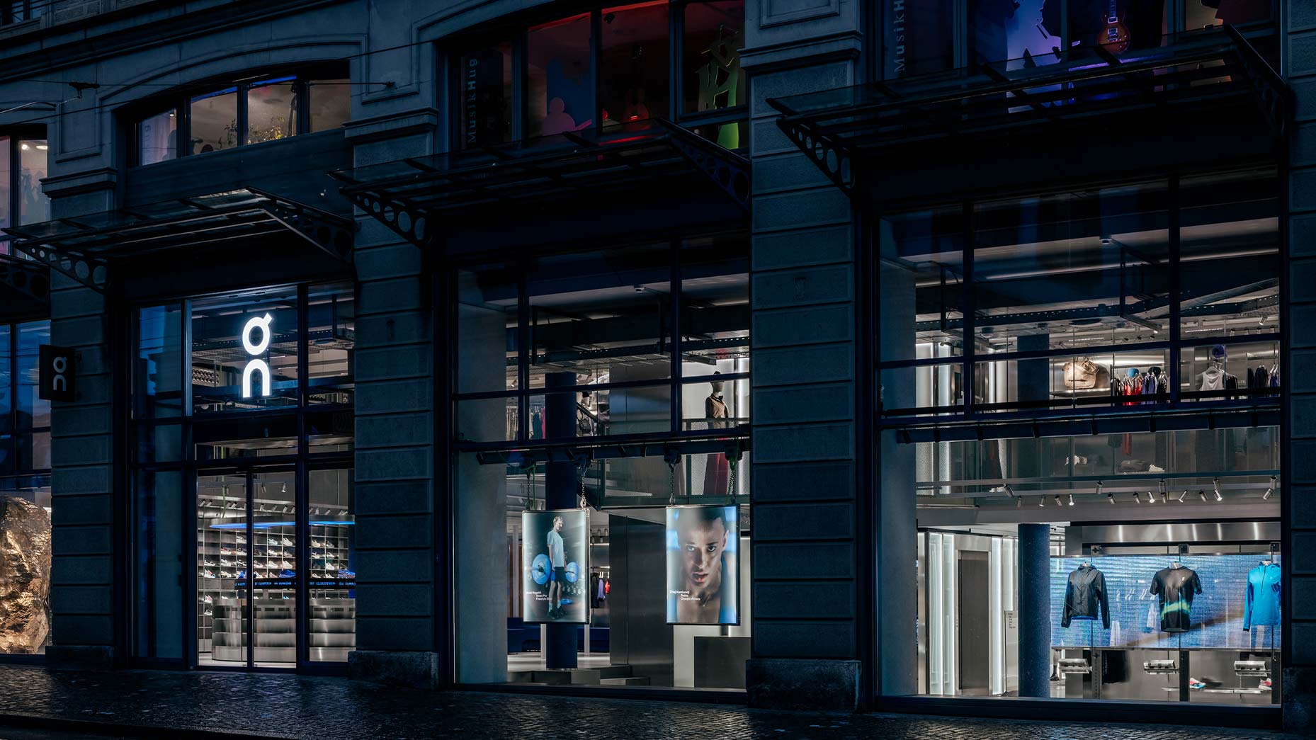 Exterior facade of On Running flagship store on Limmatquai Zurich with illuminated digital displays at night