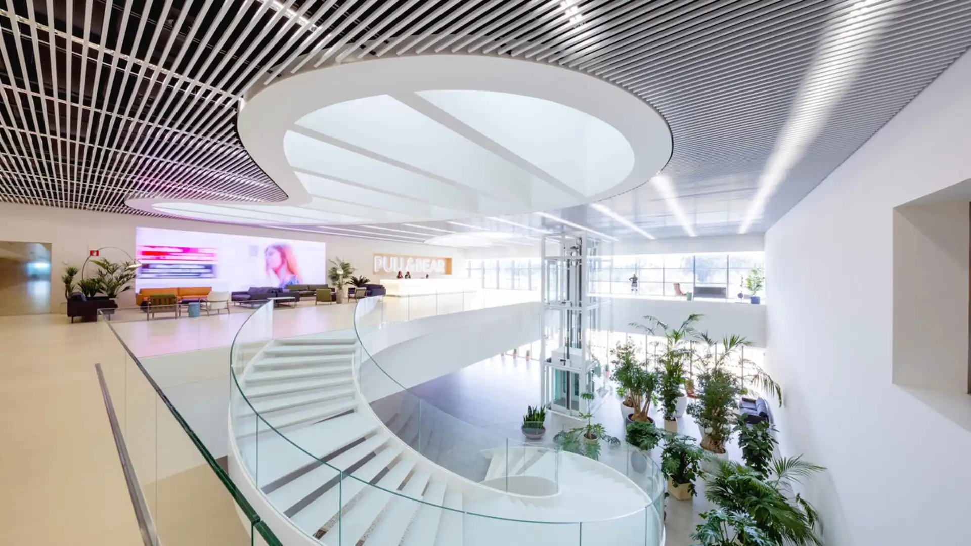 Espace de travail ouvert et durable au siège de Pull&Bear, avec lumière naturelle, verdure et conception écoénergétique.