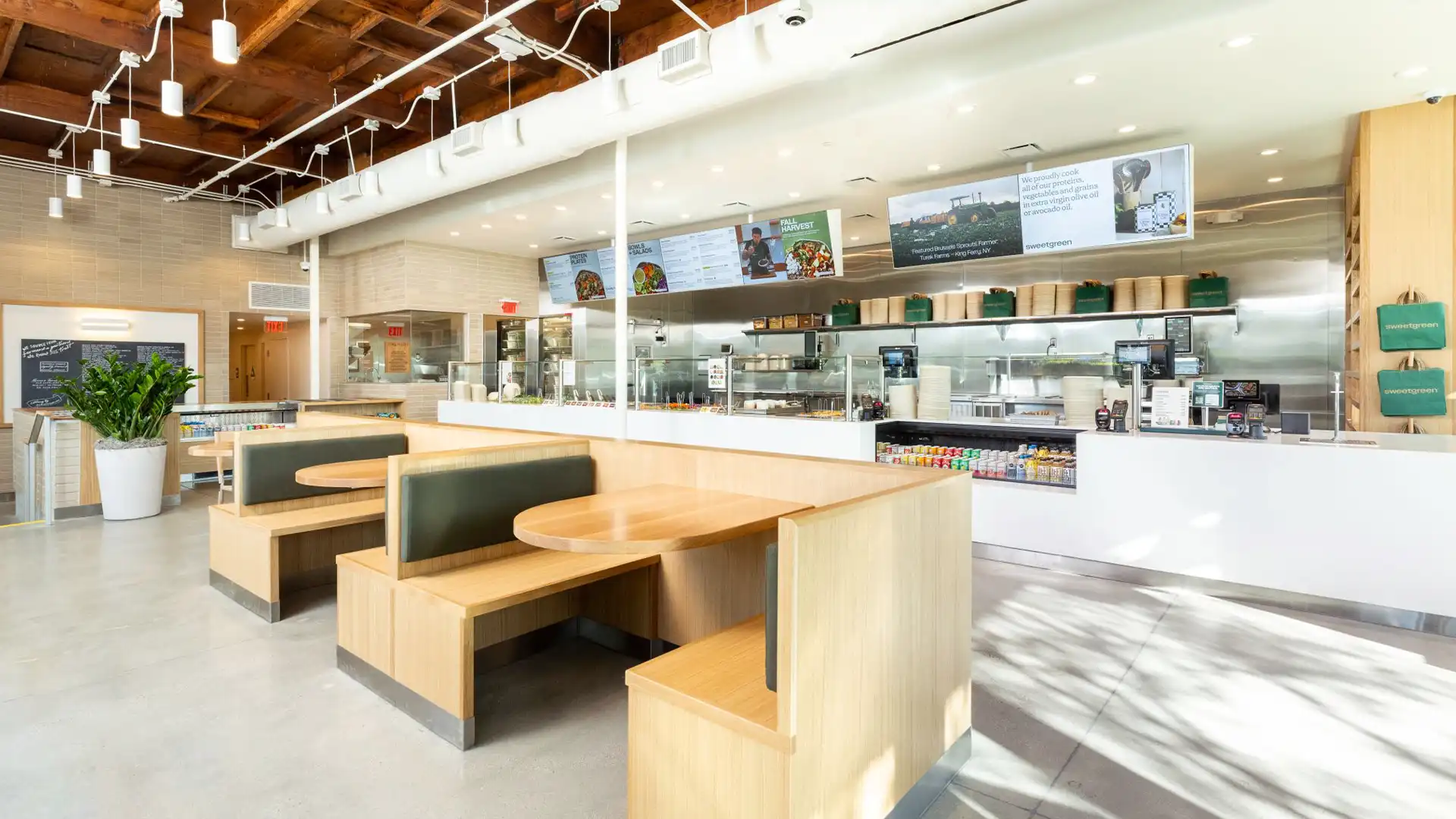 Sweetgreen-Restaurant mit Multi-Screen-Videowand, die über Nachhaltigkeitsinitiativen und Gemeinschaftsprojekte informiert.