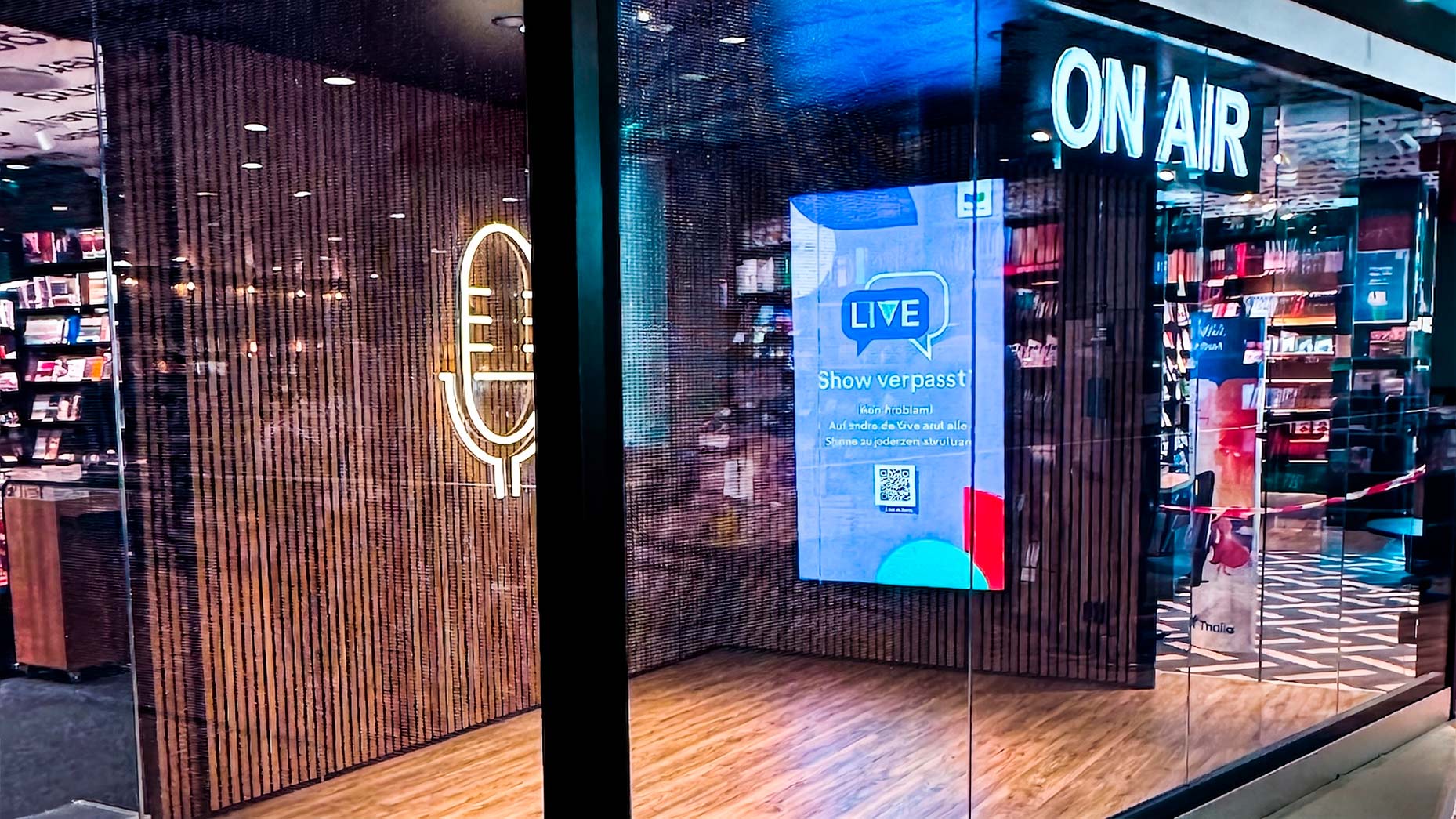 Transparent LED wall installed by TRISON at Thalia Cologne, with bookstore interior visible through the display surface