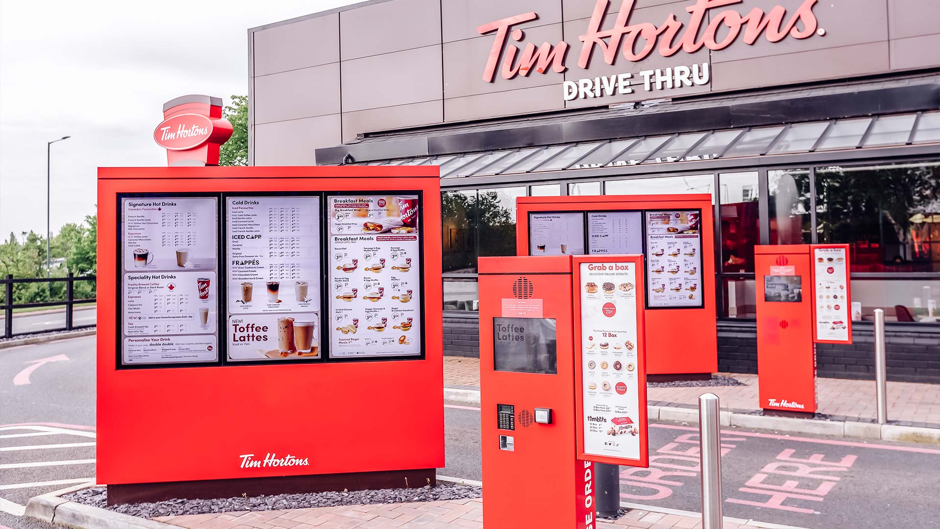 Quioscos digitales rojos de pedido drive-thru instalados por TRISON en el exterior de un restaurante Tim Hortons UK
