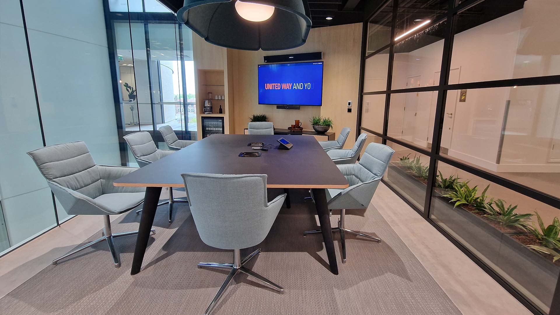 Sala de reuniones formal en la sede de Wolverine Worldwide en Londres con pantalla de gran formato y sistema de videoconferencia