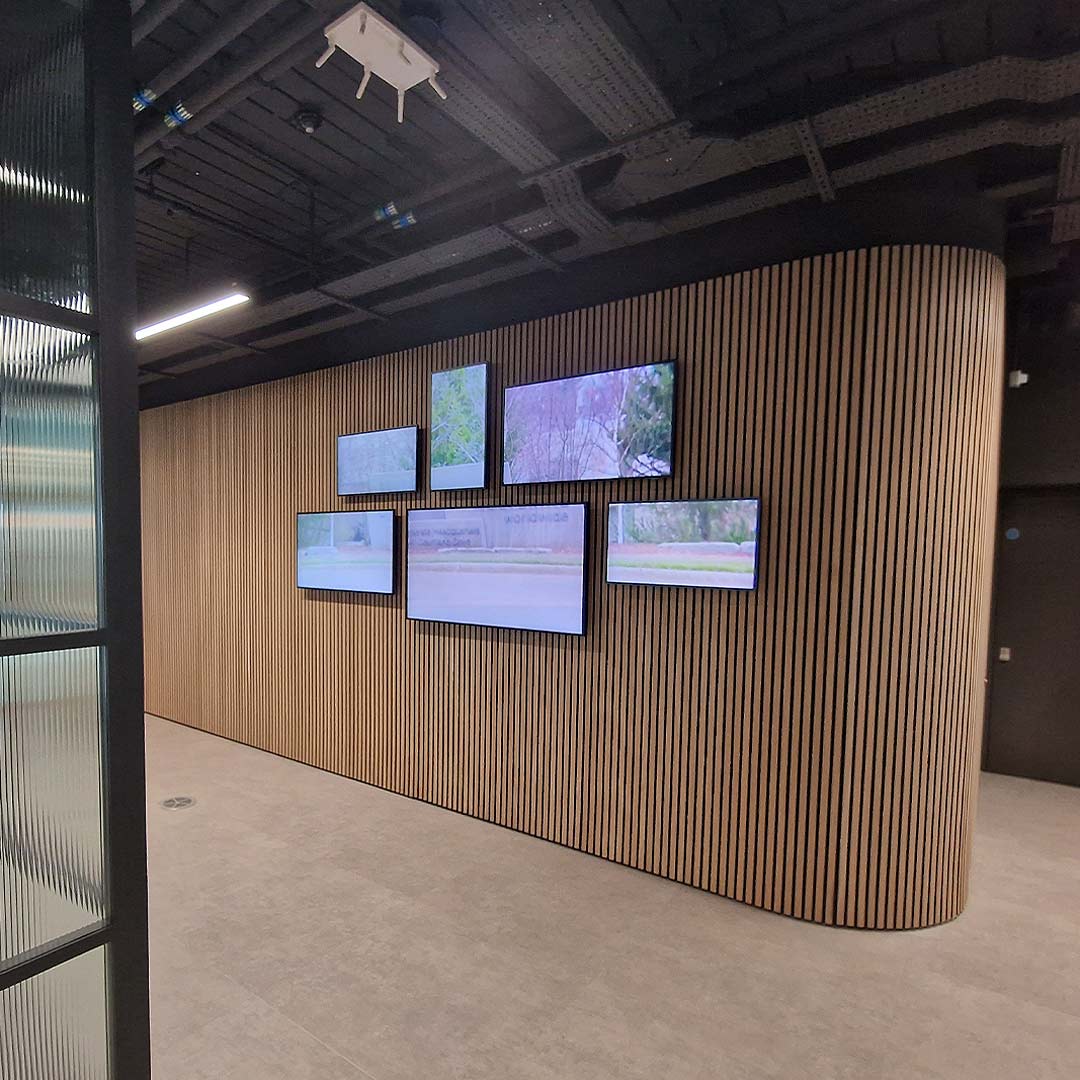 Videowall de seis pantallas sobre pared curva de madera en la sede de Wolverine Worldwide en Londres
